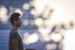 Photo of Taka looking to the right of the frame on a blue background