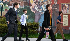 Photo of four young plaintiffs walking in front of a progressive-era mural Photo of four young plaintiffs walking in front of a progressive-era mural