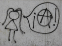 graffiti in Buenos Aires "She speaks anarchism." Graffiti stick figure girl with speech bubble inside speech bubble is anarchy symbol